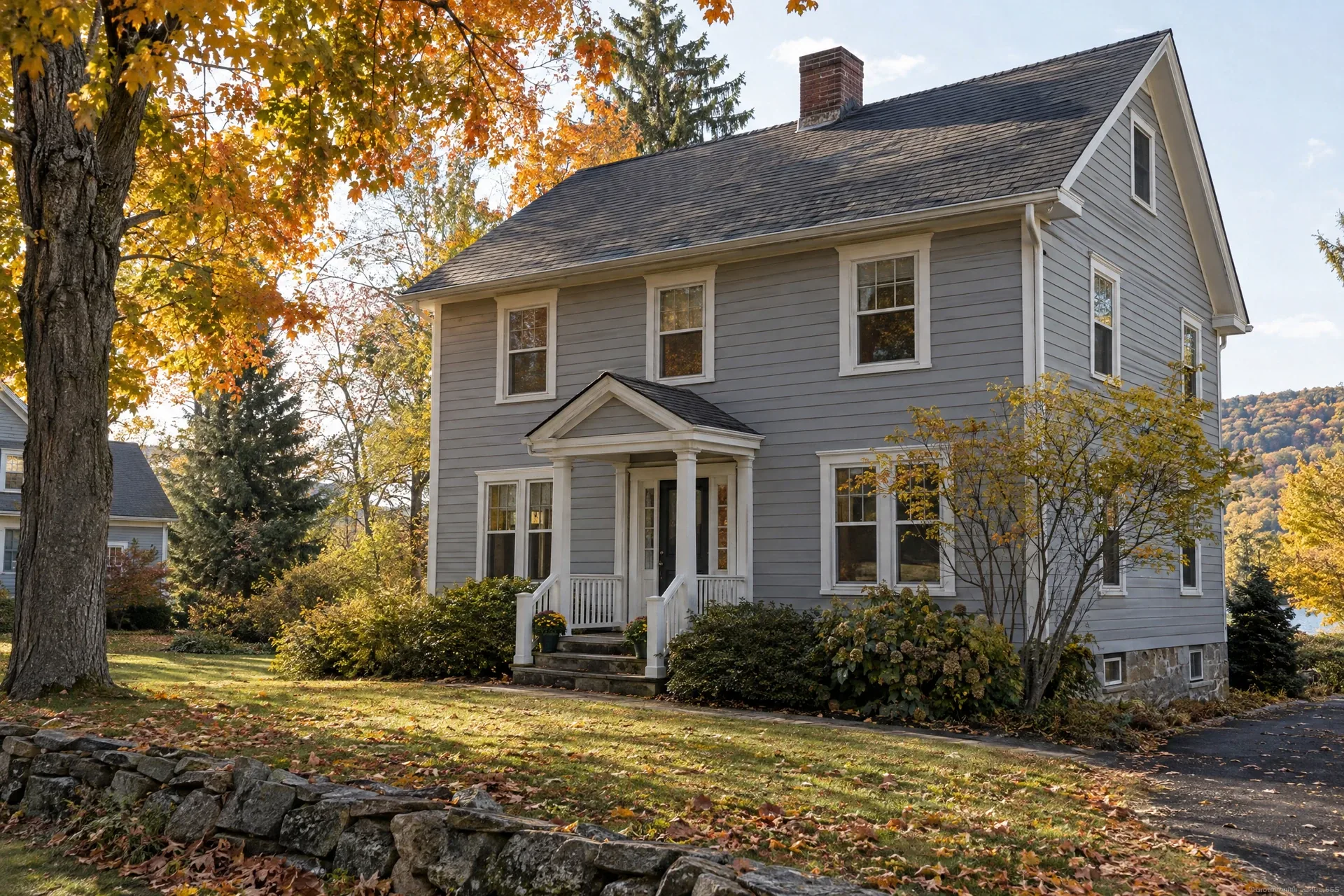 Gray clapboard house with visible roofline, chimney and stone foundation